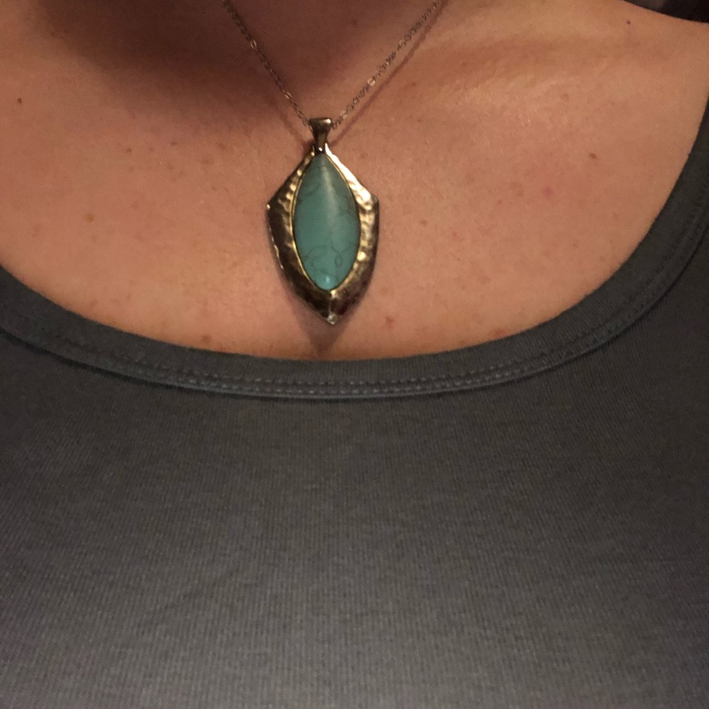 Turquoise necklace with a silver like frame around it.